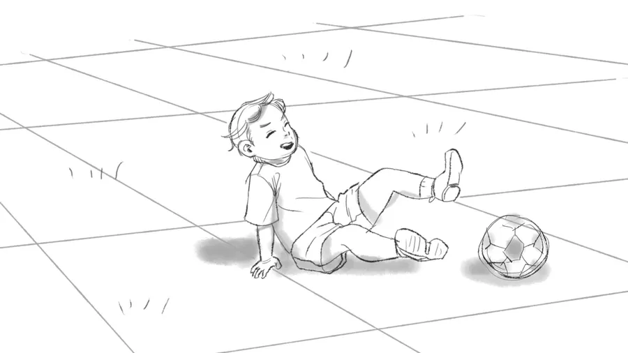 A small child sits on the floor next to a football.