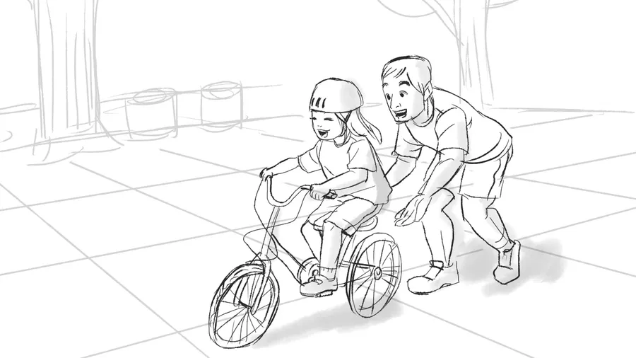 A father helps a child on a bicycle.