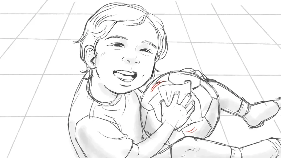 Close-up of a laughing child clutching a football.
